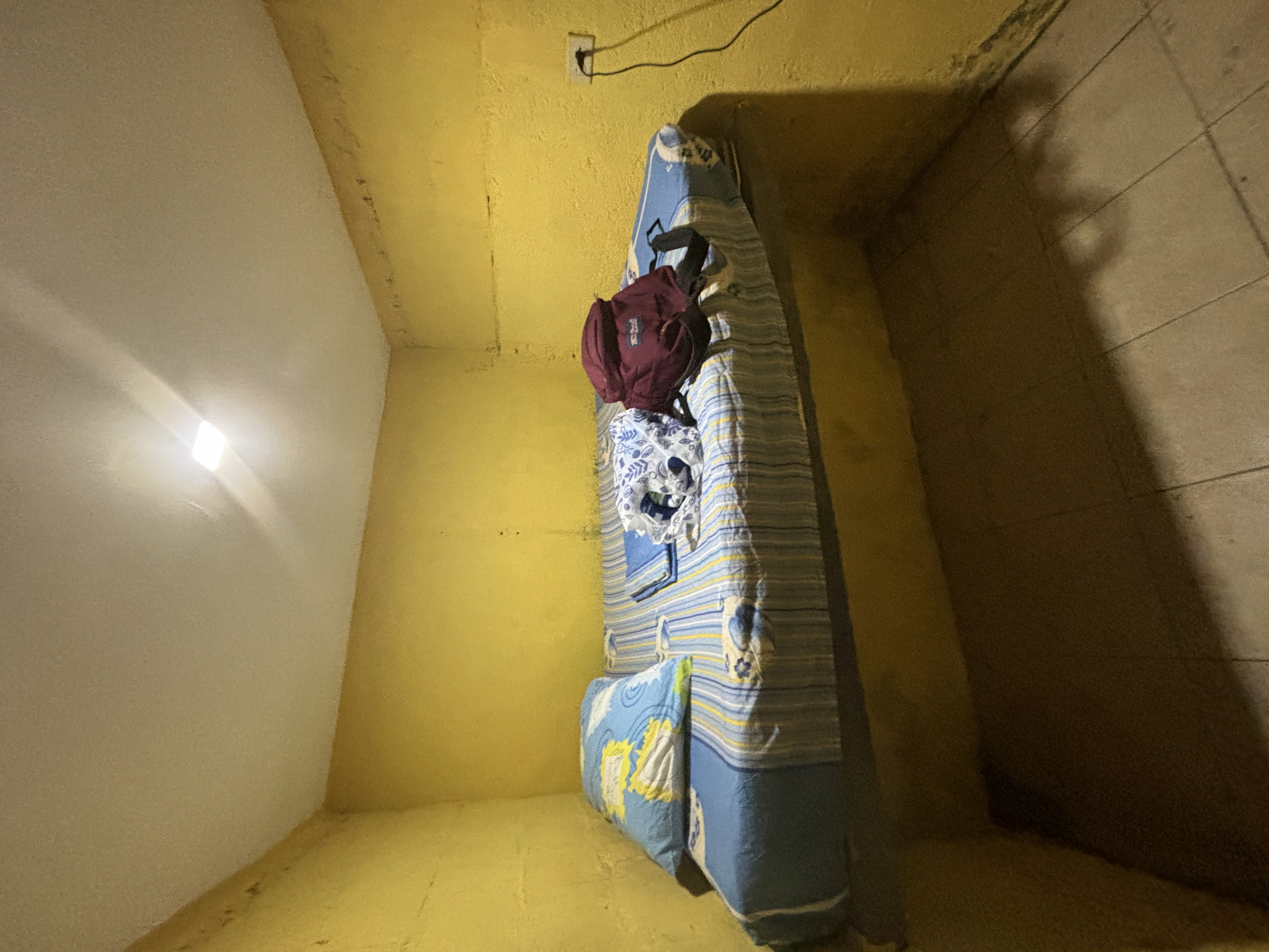 A dirty hotel room with a mattress on a concrete slab